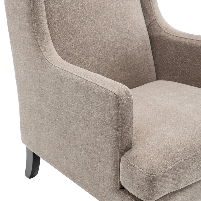 [Brand] beige upholstered armchair with curved arms and cushion.