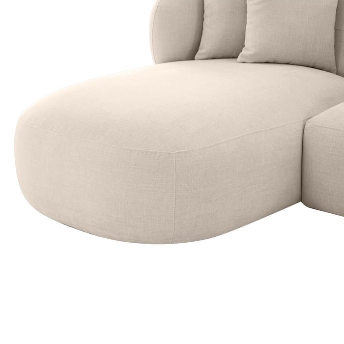 [Brand] beige sectional sofa with rounded edges and cushions.