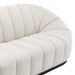 [Brand] cream tufted sofa with curved, modern design lines.