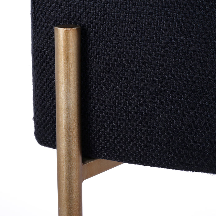 [Brand] chair leg with black fabric and gold finish.