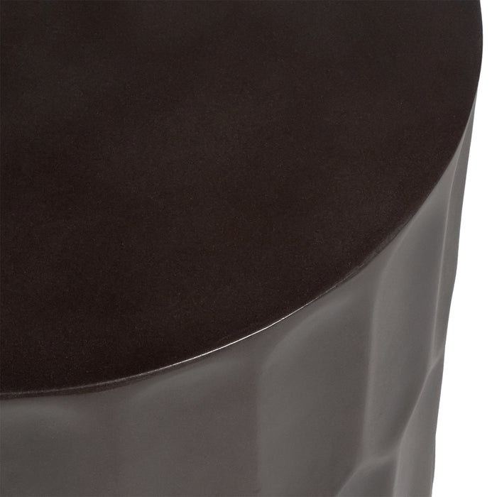 Dark, textured ceramic stool by [Brand], minimalist design detail.