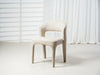 Modern beige chair by [Brand] against white curtain backdrop.
