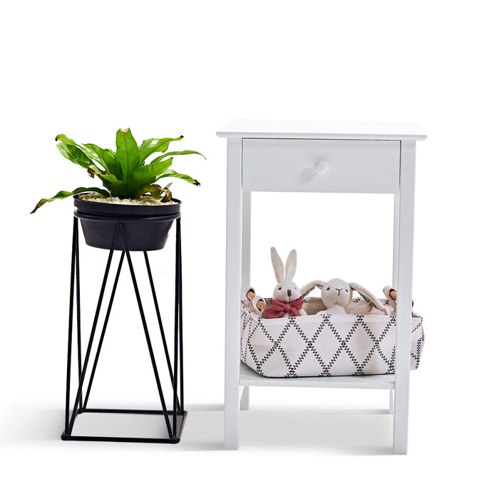 White [Brand] table, basket with toys, black plant stand.
