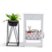 White [Brand] table, basket with toys, black plant stand.