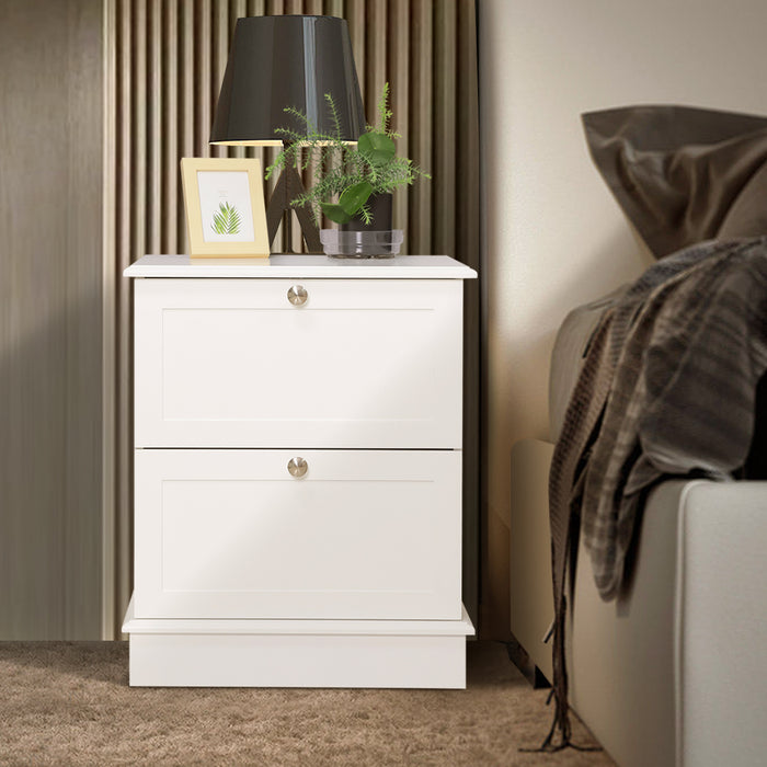 [Brand] white nightstand with lamp, plant, and picture frame.