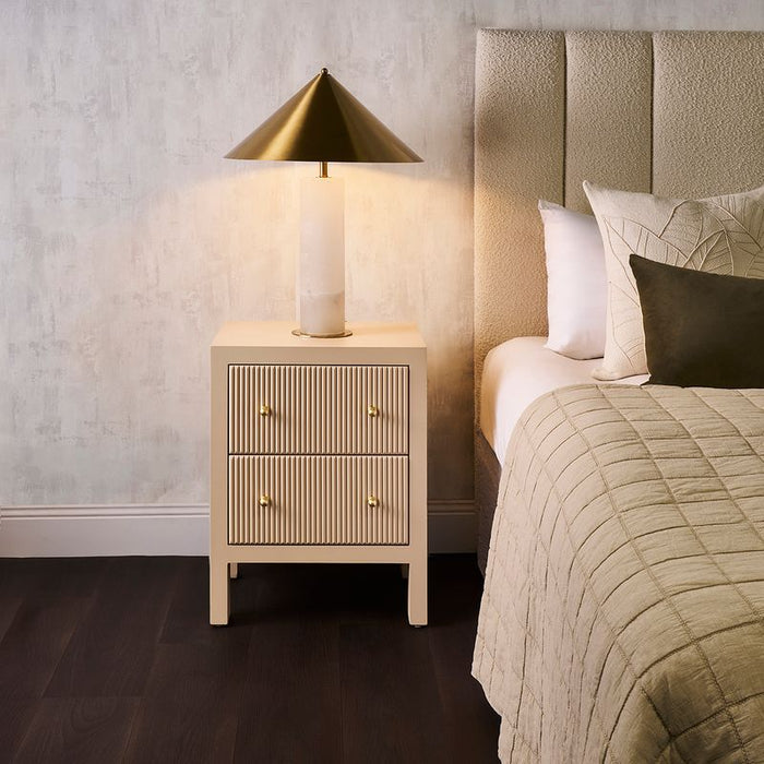 Modern bedroom with [Brand] nightstand, lamp, and cozy bedding.